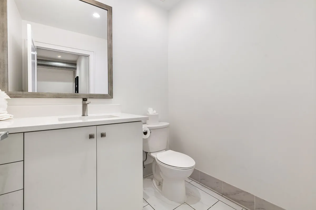 A bright and inviting half bath with a vanity, large mirror, and modern sink, complemented by elegant lighting and a sense of tranquility.