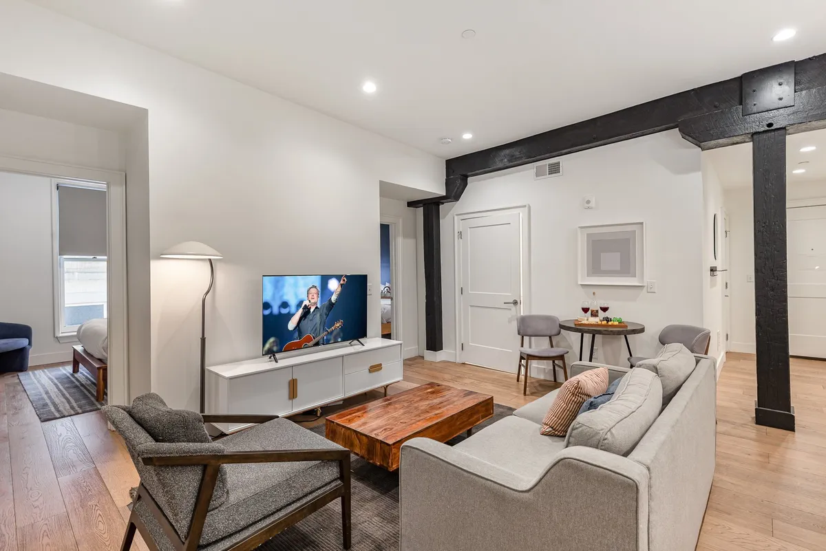 A plush living room featuring a comfortable sofa, a stylish coffee table, a modern television, and tasteful wall art. The seating area is arranged for conversation and relaxation, and the overall mood is cozy and welcoming.
