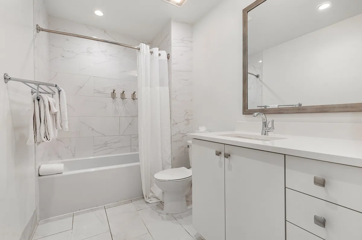 A modern bathroom featuring a sleek white bathtub, a contemporary vanity with a large mirror, and soft lighting that creates a calm and refreshing atmosphere.